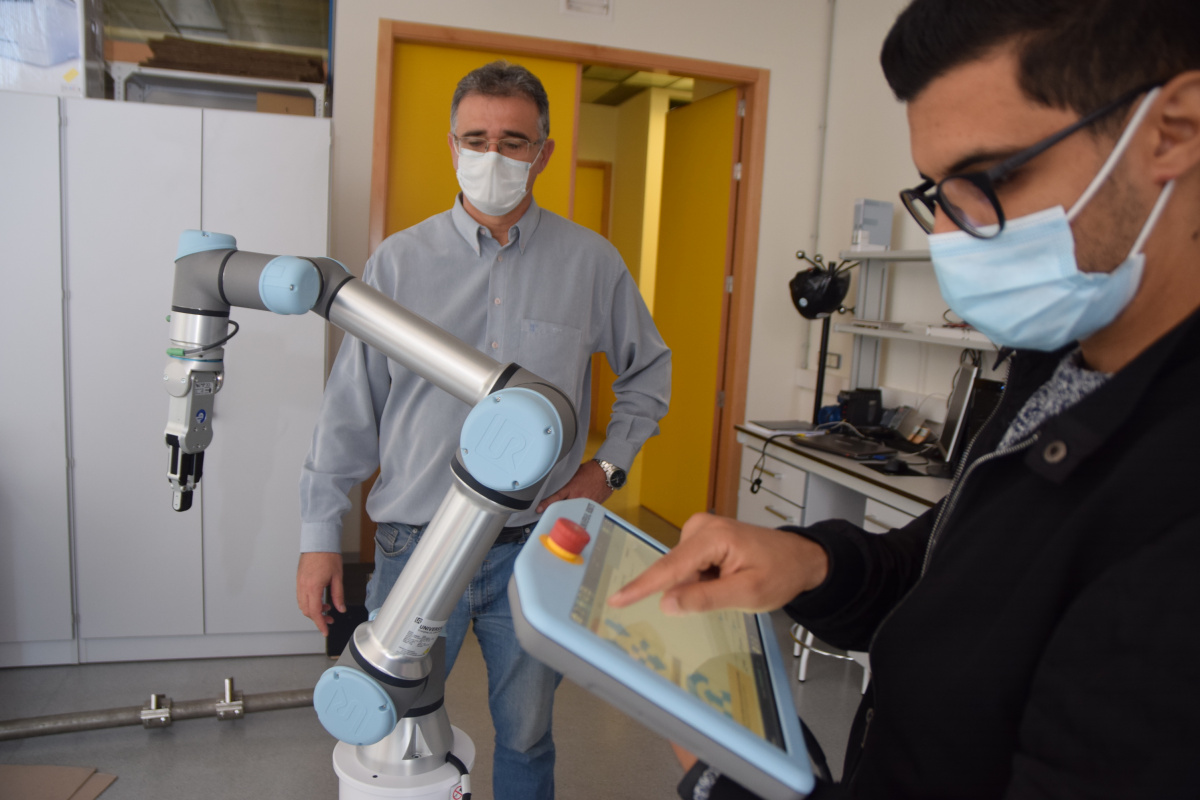 Marouane Salhaoui, en primer término, junto a uno de los directores de la tesis, Antonio Guerrero, programando un robot colaborativo.